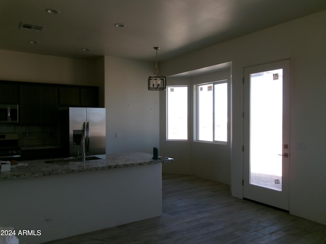 kitchen with pendant lighting, sink, light stone countertops, wood-type flooring, and stainless steel appliances