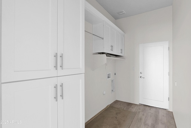 clothes washing area with hookup for an electric dryer, light hardwood / wood-style floors, cabinets, and hookup for a washing machine