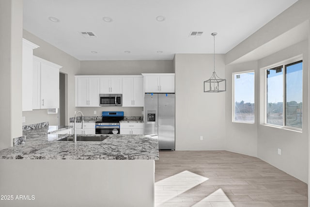 kitchen with sink, hanging light fixtures, appliances with stainless steel finishes, white cabinetry, and kitchen peninsula