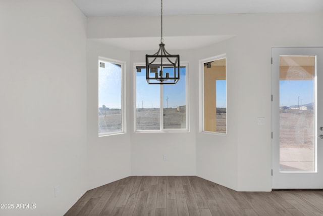 unfurnished dining area with a chandelier and wood-type flooring