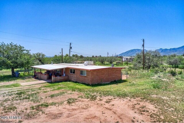 rear view of house with a mountain view, driveway, a carport, and fence