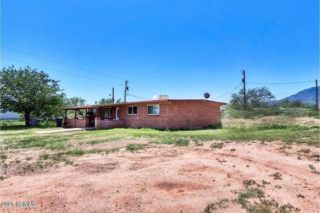 view of front of home featuring a carport, dirt driveway, and brick siding