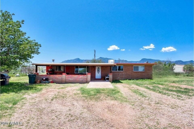 single story home featuring brick siding, a patio area, and a mountain view
