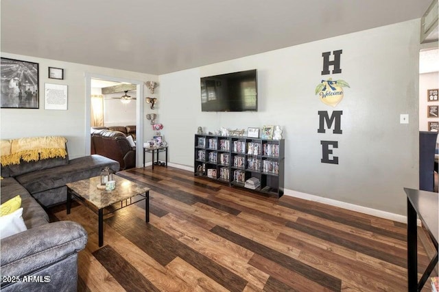 living room featuring baseboards, ceiling fan, and wood finished floors