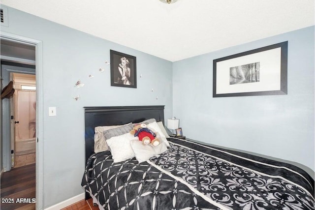 bedroom with baseboards, visible vents, and wood finished floors