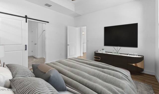 bedroom with a barn door and hardwood / wood-style floors