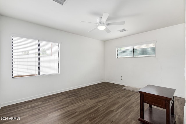 empty room featuring dark wood-style floors, visible vents, and baseboards