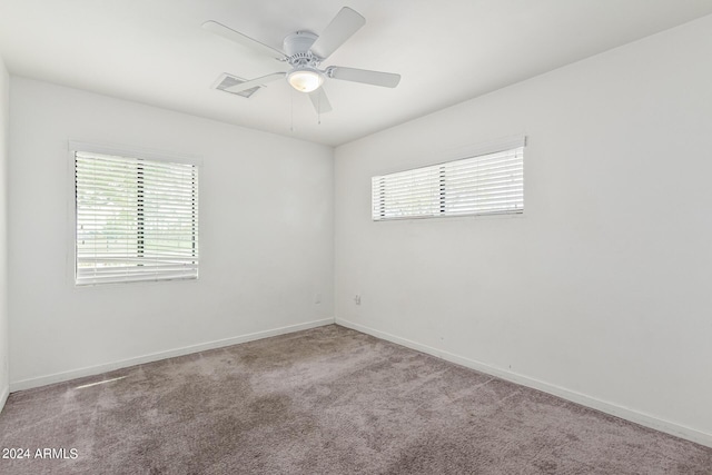 carpeted spare room featuring visible vents, ceiling fan, and baseboards