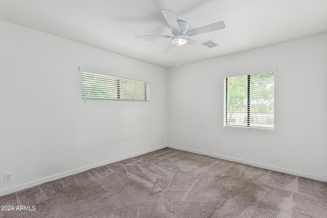 carpeted spare room featuring a ceiling fan, visible vents, and baseboards