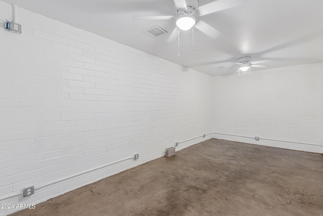 unfurnished room with brick wall, concrete floors, visible vents, and a ceiling fan