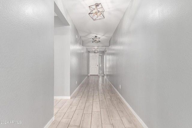 hallway featuring an inviting chandelier and light hardwood / wood-style flooring