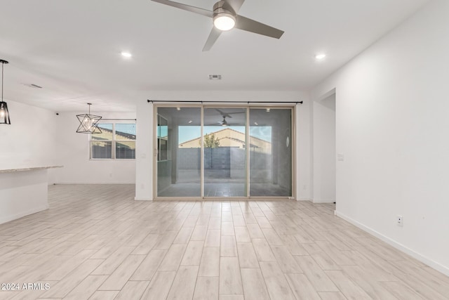 empty room featuring ceiling fan with notable chandelier