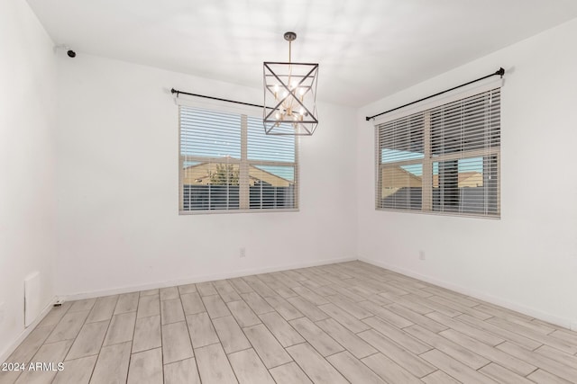 empty room with light hardwood / wood-style flooring and a chandelier