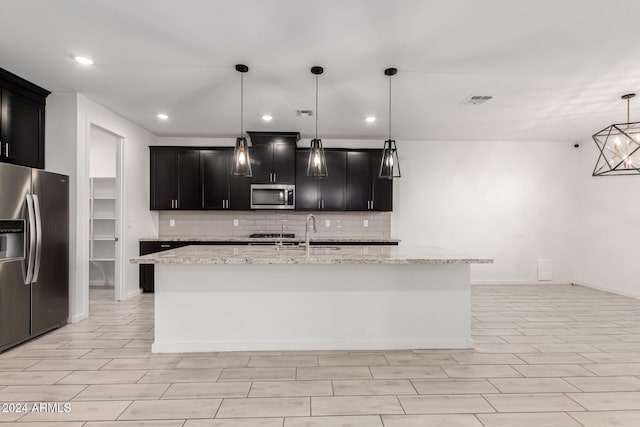 kitchen featuring stainless steel appliances, a center island with sink, pendant lighting, and light stone counters