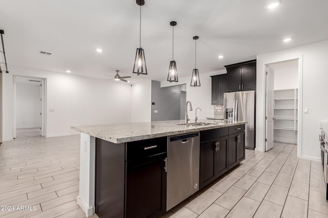 kitchen with decorative light fixtures, a kitchen island with sink, appliances with stainless steel finishes, ceiling fan, and sink