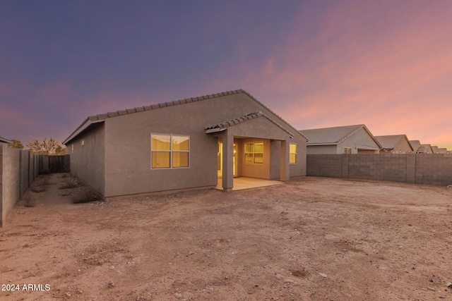 back house at dusk featuring a patio area