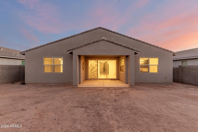 back house at dusk featuring a patio area