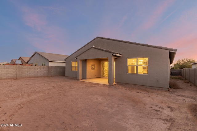 back house at dusk featuring a patio