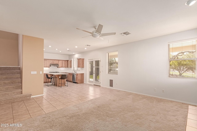 unfurnished living room with ceiling fan, sink, and light carpet