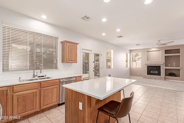 kitchen with a breakfast bar, sink, light tile patterned floors, dishwasher, and a kitchen island