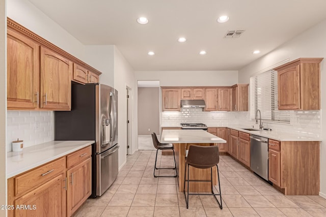 kitchen featuring a kitchen bar, sink, light tile patterned floors, a kitchen island, and stainless steel appliances