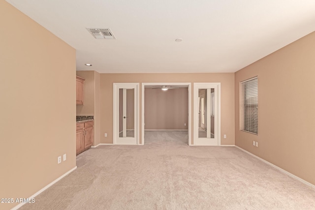 spare room featuring light carpet and french doors