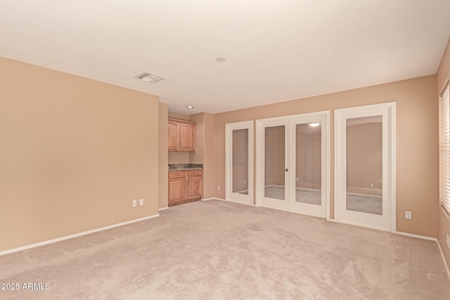 unfurnished living room with light carpet and french doors