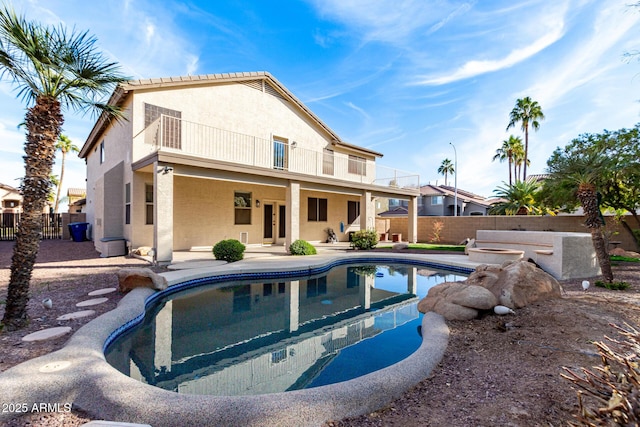 rear view of house featuring a balcony, a fenced in pool, and a patio area