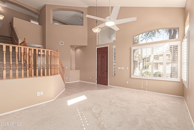 carpeted foyer with ceiling fan and a towering ceiling