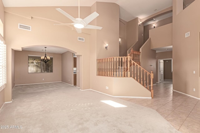 unfurnished living room featuring high vaulted ceiling, ceiling fan with notable chandelier, and light tile patterned floors