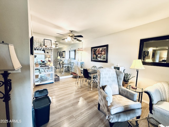 living room featuring baseboards, a ceiling fan, and wood finished floors