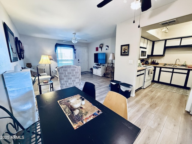 dining space with visible vents, light wood-style flooring, and a ceiling fan