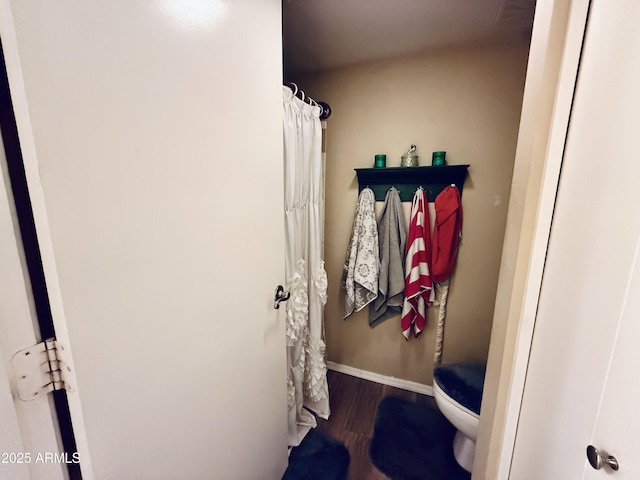 full bathroom with curtained shower, baseboards, toilet, and wood finished floors