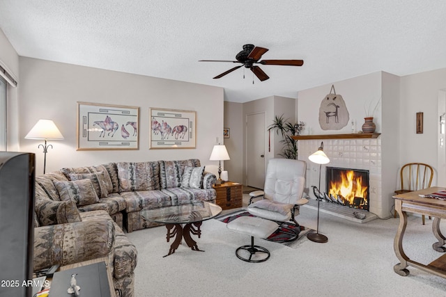 living room featuring a brick fireplace, carpet floors, a textured ceiling, and ceiling fan