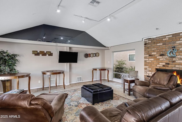 living room featuring a fireplace, vaulted ceiling, and light tile patterned floors