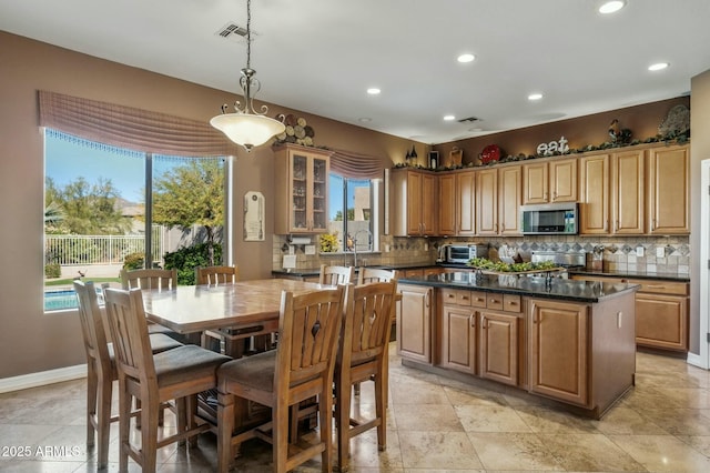 4502 E Night Owl Ln, Cave Creek, AZ 85331 - kitchen with decorative light fixtures, a kitchen island, visible vents, stainless steel microwave, and glass insert cabinets