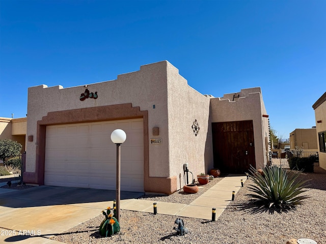 adobe home with a garage, driveway, and stucco siding