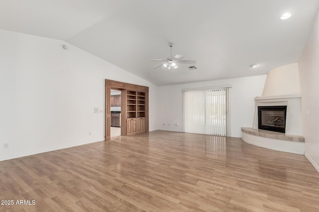 unfurnished living room with ceiling fan, a large fireplace, light hardwood / wood-style floors, and vaulted ceiling