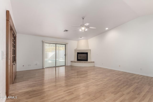 unfurnished living room featuring ceiling fan, a large fireplace, lofted ceiling, and light hardwood / wood-style flooring