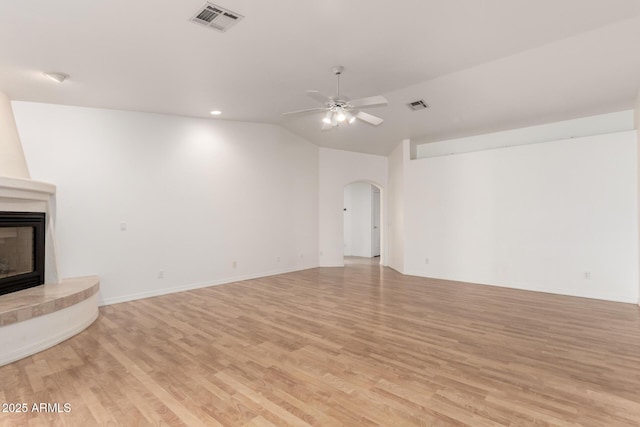 unfurnished living room with a large fireplace, light hardwood / wood-style flooring, vaulted ceiling, and ceiling fan