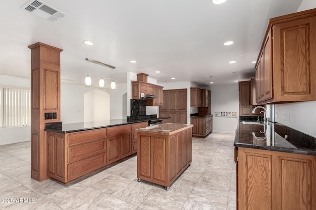 kitchen with kitchen peninsula, a kitchen island, hanging light fixtures, and sink