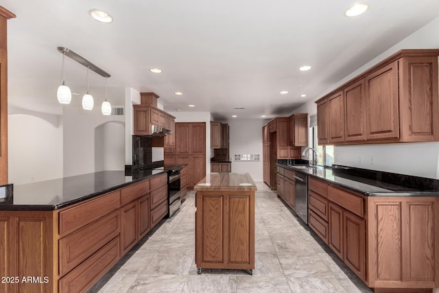 kitchen with kitchen peninsula, stainless steel appliances, sink, decorative light fixtures, and a center island