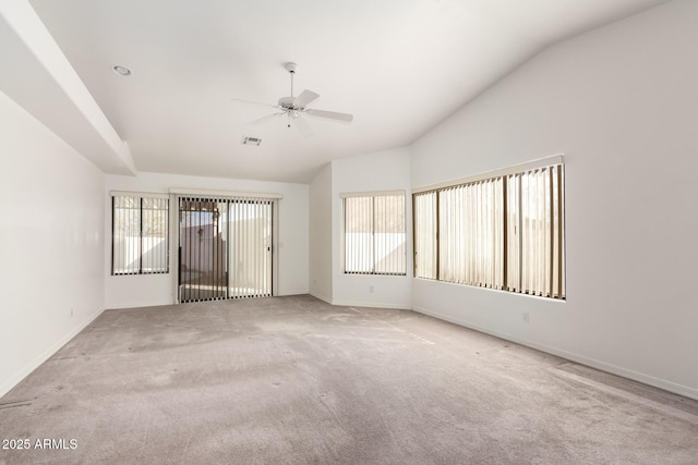 carpeted spare room with a wealth of natural light, vaulted ceiling, and ceiling fan