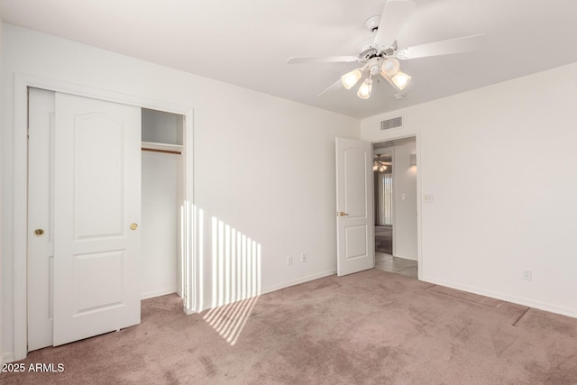 unfurnished bedroom featuring ceiling fan, a closet, and light carpet