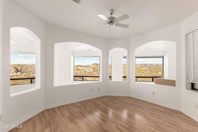 spare room featuring ceiling fan, a wealth of natural light, and light hardwood / wood-style flooring