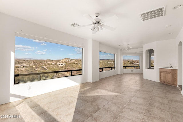 unfurnished living room featuring ceiling fan, light tile patterned floors, and sink