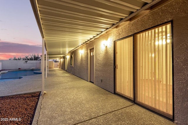 patio terrace at dusk featuring a fenced in pool