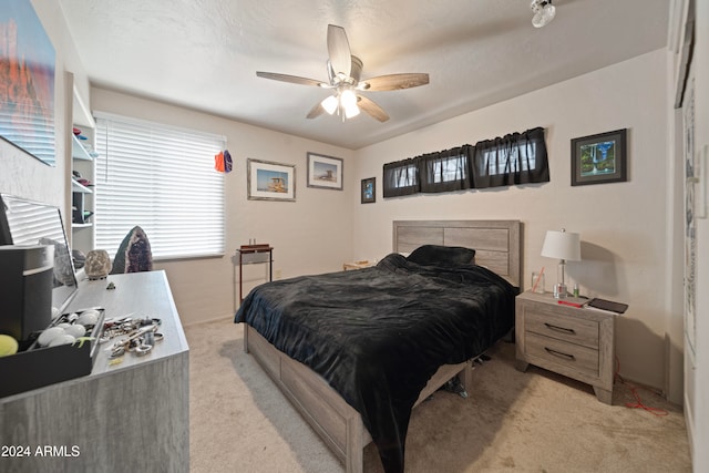 bedroom featuring ceiling fan, light colored carpet, and a textured ceiling