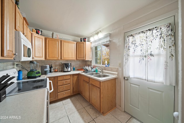 kitchen featuring tasteful backsplash, sink, light tile patterned floors, and range