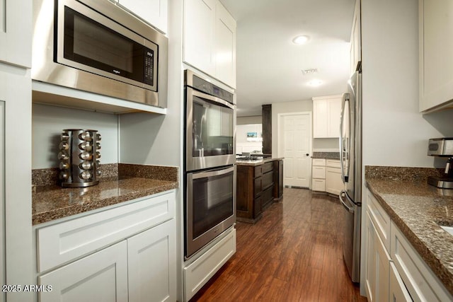 kitchen featuring stainless steel appliances, dark hardwood / wood-style flooring, white cabinets, and dark stone counters